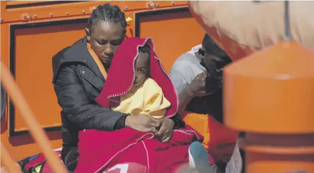  ??  ?? 0 A migrant woman and a child keep warm upon their arrival aboard a coast guard boat at Malaga’s harbour after an inflatable boat was rescued off the Spanish coast