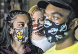  ?? L.E. Baskow Las Vegas Review-Journa @Left_Eye_Images ?? Gloria Reyes, left, Kristin McCormick, center, and Mykel Lewis model the three masks available at the Hard Rock Cafe on the Strip, as well as the company’s website.