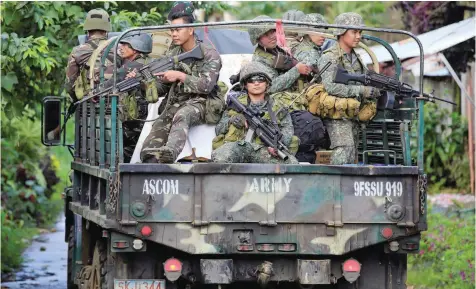  ?? — Reuters ?? Government soldiers are seen on a military truck as they continue their assault on insurgents from the Maute group, who have taken over large parts of Marawi City, Philippine­s, on Thursday.