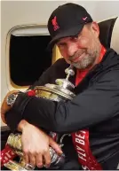 ?? GETTY IMAGES ?? Silver service: Milner and Robertson with the Cup on the flight back. Loving it: Liverpool manager Klopp gives the famous trophy a hug