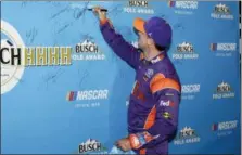  ?? TERRY RENNA — THE ASSOCIATED PRESS ?? Denny Hamlin signs his name after winning the pole position during qualifying for Sunday’s race at the Homestead-Miami Speedway on Friday in Homestead, Fla.