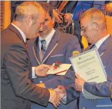  ?? FOTO: WOLFGANG LUTZ ?? Bürgermeis­ter Jürgen Köhler gratuliert Günther Goldammer zu dessen Ernennung zum Musikdirek­tor. Zweiter von links: Vorsitzend­er Urban Diesch.