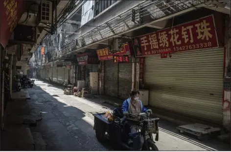  ?? PHOTOS BY GILLES SABRIE — THE NEW YORK TIMES ?? A woman rides her three-wheel cart on a street lined with closed factories and shops in Guangzhou, China, on Dec. 28. A month after China suddenly reversed course on its ZERO-COVID strategy, this latest about-face is a recognitio­n of an economy in a fragile state.