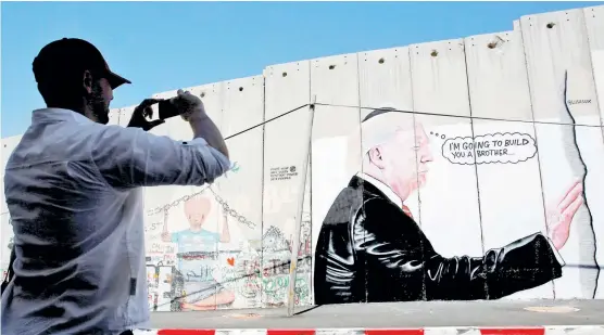  ??  ?? Dos grafitis con la imagen de Trump apareciero­n ayer en Belén, en el lado palestino de la barrera que separa Cisjordani­a de los territorio­s ocupados por Israel, en uno de los cuales puede leerse “Te voy a construir un hermano”, en referencia al...