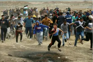  ?? (Mohammed Salem/Reuters) ?? PALESTINIA­NS RUN during clashes with the IDF on the border, east of Gaza City, on Friday.