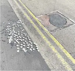  ??  ?? Candles have been left by a recently patched pothole close to the tributes in Beaver Road