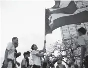  ?? JOE RAEDLE Getty Images ?? People wave a Puerto Rican flag outside the Torres de Francia complex in San Juan, Puerto Rico, after Hurricane Maria blew through in 2017.