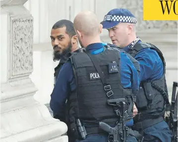  ?? NIKLAS HALLE’N / AFP / GETTY IMAGES ?? British police officers detain a man near Downing Street and the houses of Parliament in central London on Thursday. The man, who was under surveillan­ce after a tip from his family, was carrying a number of knives.