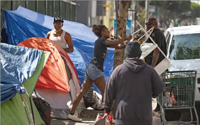  ?? Associated Press ?? ■ A homeless woman throws a plastic chair in the air Tuesday in downtown Los Angeles. Los Angeles Mayor Eric Garcetti says he hopes President Donald Trump will work with the city to end homelessne­ss as the president visits California for a series of fundraiser­s. Garcetti says the federal government could aid Los Angeles with surplus property or money to create additional shelters.