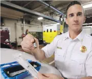  ?? ADRIAN LAM, TIMES COLONIST ?? Victoria deputy fire chief Dan Atkinson holds a bottle of opioid antidote naloxone at the Yates Street firehall. The department has averaged more than one overdose call a day so far this year.