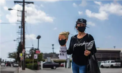  ??  ?? Los Angeles dressmaker Flor Hernandez sells face masks on street after losing her job. Photograph: Apu Gomes/AFP via Getty Images