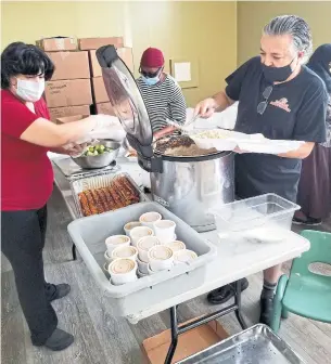  ?? DELTA FAMILY RESOURCE CENTRE PHOTOS ?? Monir and Ahmed (foreground, left to right) of local restaurant Afghan Kebob work with volunteer Joy to put together freshly prepared meals for the Feed the Frontlines TO initiative, in part funded by the government of Canada through the United Way-administer­ed Emergency Community Support Fund.