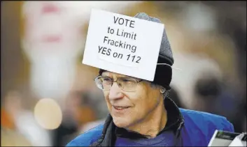  ?? David Zalubowski The Associated Press ?? Chris Hoffman wears a sign to promote a propositio­n to limit fracking, while attending a rally Wednesday at the University of Colorado in Boulder.