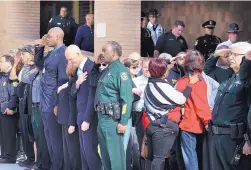  ?? JOE BURBANK/ORLANDO SENTINEL ?? Florida Gov. Rick Scott bows his head and Orange County Sheriff Jerry Demings, center, salutes as a slain deputy is transporte­d from a hospital Monday.