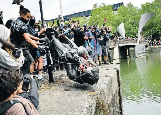  ?? BEN BIRCHALL / AP ?? Los manifestan­tes lanzan a las aguas del puerto británico de Bristol una estatua de un esclavista del siglo XVII, tras derribarla de su pedestal