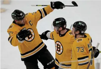  ?? STuART cAHiLL / HERALd STAFF; BELoW, nAncy LAnE / HERALd STAFF ?? GOOD PAIRING: Matt Grzelcyk, center, celebrates scoring in the second period of Saturday’s 3-2 win over Buffalo with Charlie McAvoy (73) and Patrice Bergeron. Below, Jakub Zboril battles for control of the puck with New Jersey’s Janne Kuokkanen during the first period of Sunday’s game.