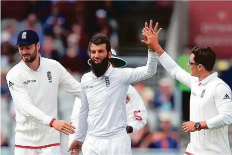  ?? AFP ?? England’s Moeen Ali (centre) celebrates with teammates after removing Pakistan’s Younis Khan on the fourth day of the second Test at Old Trafford in Manchester yesterday.