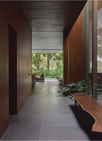 ??  ?? This page
Basalt flooring and walnut-clad walls figure throughout the home. Here the natural materials are emphasised with an organic bench by George Nakashima and planted greenery that echoes the nature outside
