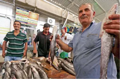  ??  ?? A vendor sells fish at a market in east Mosul. Merchants and shoppers have mixed feelings about what the future holds for Iraq. —