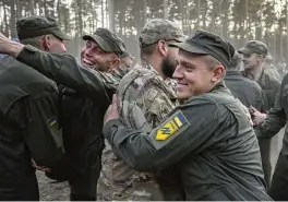  ?? EFREM LUKATSKY/AP ?? Newly recruited soldiers hug each other as they celebrate the end of their training Sept. 25, 2023. As the third year of war begins, the most sensitive and urgent challenge pressing on Ukraine is whether it can muster enough new soldiers.