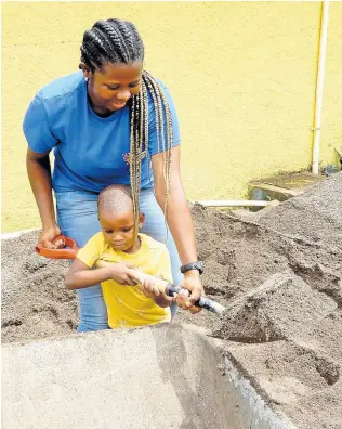  ?? PHOTO BY CARL GILCHRIST ?? Three-year-old Aiden Meeks was adamant that he had to share his mom’s (Ann-Marie Campbell) work on Labour Day at the Eltham Early Childhood Institutio­n in St Ann. She had to relent.