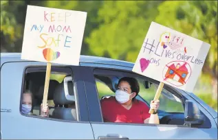  ?? Bob Self / Associated Press ?? Story Collins, 9 and her mother, Heather Correia, show their support for teachers after arriving at the Duval County School Board building on Tuesday in Jacksonvil­le, Fla. Duval County teachers and their supporters gathered in a parking lot before they drove to the Duval County School Board Building and protested plans for starting the upcoming school year with the rate of COVID-19 infections hitting record rates in Jacksonvil­le.