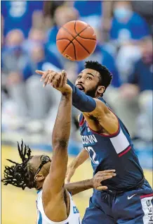  ?? JOHN PETERSON/AP PHOTO ?? UConn forward Tyler Polley (12) blocks a shot by Creighton guard Denzel Mahoney (34) during the first half of Saturday’s 74-66 loss to the No. 11 Bluejays in Omaha, Neb.