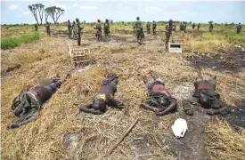  ?? — AFP ?? MALAKAL: Soldiers of the Sudan People Liberation Army (SPLA) patrol near to dead bodies of rebel soldiers in Lelo, outside Malakal, northern South Sudan.