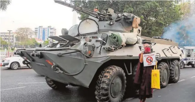  ?? REUTERS ?? Un monje budista muestra un cartel contra el golpe de Estado ante un vehículo blindado durante una protesta en Rangún