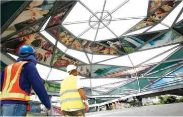  ??  ?? CIRCULO’S END — Constructi­on workers walk yesterday inside the Circulo del Mundo Rotunda, which will be demolished to give way to the constructi­on of the elevated skyway on Andrew Avenue in Villamor, Pasay City. (KJ Rosales)