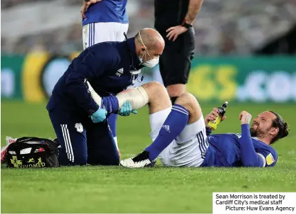  ??  ?? Sean Morrison is treated by Cardiff City’s medical staff
Picture: Huw Evans Agency