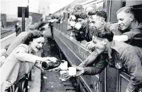  ??  ?? > A welcome drink for troops as the train pulls up at a railway station after the evacuation of Allied soldiers from the beaches and harbour of Dunkirk