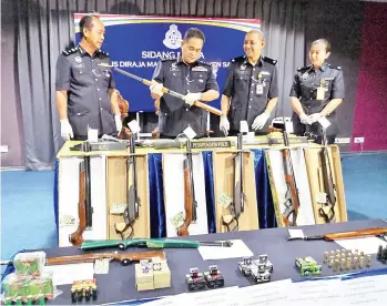  ??  ?? Omar (second left) inspecting an airgun as Jauteh (left) and Ahmad Jawilah (second right) look on.