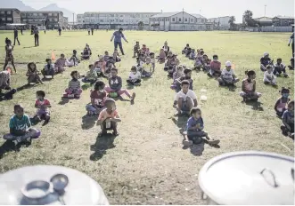  ?? Picture: AFP ?? Children line up in rows as volunteers of the Lavender Hill Sport and Recreation Foundation arranges them in Lavender Hill, Cape Town, yesterday during a food distributi­on initiative.