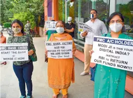  ?? —AFP ?? Depositors and account holders of Punjab and Maharashtr­a Co-operative Bank hold placards during a protest near the Reserve Bank of India in New Delhi on Wednesday. On Tuesday, the central bank said net worth erosion, steep fall in deposits posed serious challenges in finding a workable plan for the revival of the fraud-hit bank.