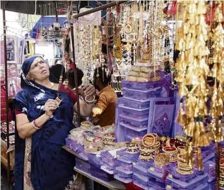  ?? ?? Scorched . . . Kamlaben Ashokbhai Patni adjusts imitation jewellery at a stall in a market in Ahmedabad, India. When the heat becomes extreme, brass jewellery on display in her stall is damaged.