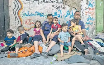  ?? AP ?? A Palestinia­n family sits outside their home after it was hit by an early morning Israeli airstrike in Gaza City on Monday.