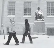  ?? JOSH REYNOLDS AP ?? Pedestrian­s walk past the statue of John Harvard on Saturday in Harvard Yard in Cambridge, Massaschus­etts, during a storm that was projected to bring up to two feet of snow to New England.