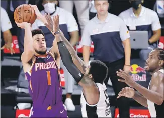  ?? Kevin C. Cox Associated Press ?? THE SUNS’ Devin Booker shoots the game-winning basket over the outstretch­ed hand of Paul George just before the final buzzer sounded, dropping the Clippers to 1-2 during the NBA restart.