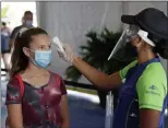  ?? JOHN RAOUX — THE ASSOCIATED PRESS ?? A girl has her temperatur­e checked before entering the newly reopened SeaWorld park in Orlando, Fla., on Thursday.