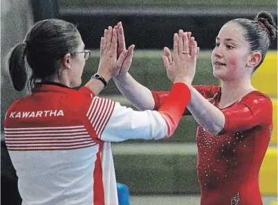  ?? CLIFFORD SKARSTEDT EXAMINER FILE PHOTO ?? Ava Hanley high-fives her coach after performing on the beam during the Kawartha Gymnastics Club’s Swingin' Safari Invitation­al Meet on March 2019. The club is moving to a new facility on High Street.