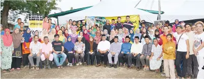  ??  ?? BERGAMBAR beramai-ramai bersama sukarelawa­n Yosh, penduduk kampung dan Taib (duduk, tengah).