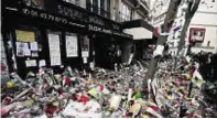  ??  ?? Crowds look at flowers left at the La Belle Equipe bar