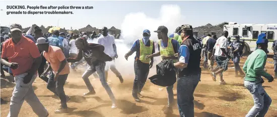 ??  ?? DUCKING. People flee after police threw a stun grenade to disperse troublemak­ers.