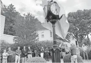  ?? PHILIP DEVENCENTI­S/NORTHJERSE­Y.COM ?? Mayor John Lane pulls off a canvas tarp to unveil the new street clock at the ceremony last Wednesday.
