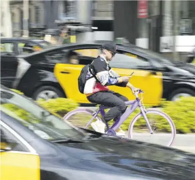  ?? Jordi Cotrina ?? Un ciclista manipula el telèfon mòbil mentre pedala pel carril bici de la Diagonal, ahir.