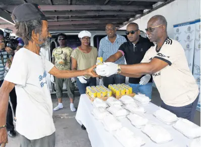  ?? BY IAN ALLEN/PHOTOGRAPH­ER PHOTOS ?? Michael Beckles (left) collects breakfast and a drink from Desmond McKenzie (right), minister of local government and community developmen­t, and Duane Smith, councillor for the Chancery Hall division, on Sunday.