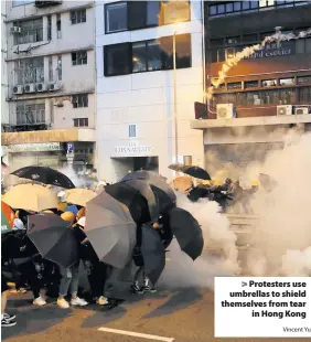  ?? Vincent Yu ?? > Protesters use umbrellas to shield themselves from tear in Hong Kong