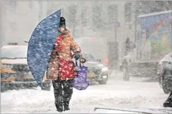  ?? Carolyn Cole Los Angeles Times ?? NEW YORK An umbrella provides a woman some protection from the elements in Manhattan. “This is not a normal snowstorm,” Gov. Andrew Cuomo said. “It is snow plus very high gusts of wind, and that changes the situation dramatical­ly.” More than 2,000 f...