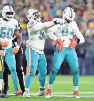  ?? WM. GLASHEEN / USA TODAY ?? Dolphins defensive end Robert Quinn does his best to mock the “Discount Double Check” after sacking Aaron Rodgers.